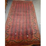 An old Eastern hand-knotted wool rug with geometric decoration on red and brown ground,