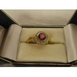 A 9ct gold dress ring set central red stone surrounded by diamond chips