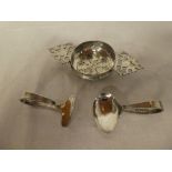 A silver circular tea strainer with pierced handles,