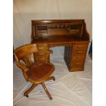 An Edwardian oak roll-top desk with fitted interior enclosed by a tambour front with a small drawer