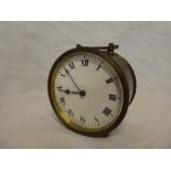A small brass cased travelling clock with circular enamelled dial and loop handle
