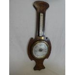 A good quality aneroid barometer with silvered circular dial below thermometer in inlaid mahogany