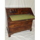 A George III figured mahogany bureau with numerous small drawers and pigeonholes enclosed by a fall