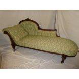 A mid Victorian carved mahogany chaise longue with green floral buttoned fabric on turned legs and