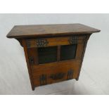 An Art Nouveau oak smokers cabinet with two internal drawers enclosed by a coloured glass panelled