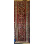 An old Eastern hand-knotted wool runner with floral decoration on red and blue ground,