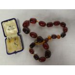 A red amber graduated bead necklace with a pair of silver earrings set pearls