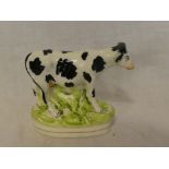 A 19th Century Staffordshire pottery figure of a black and white cow on rustic base,