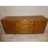 A 1960's Ercol light elm rectangular sideboard with three central drawers and cupboards enclosed by