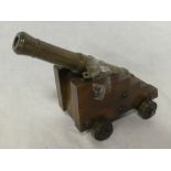 An old bronze model canon with 7" barrel on polished wood stepped base with brass mounted wheels