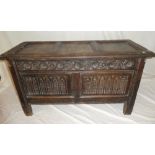 An 18th Century carved oak rectangular coffer with twin panelled front and hinged lid on block feet