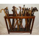 A mahogany three-section stick stand containing a collection of over 40 various walking sticks and