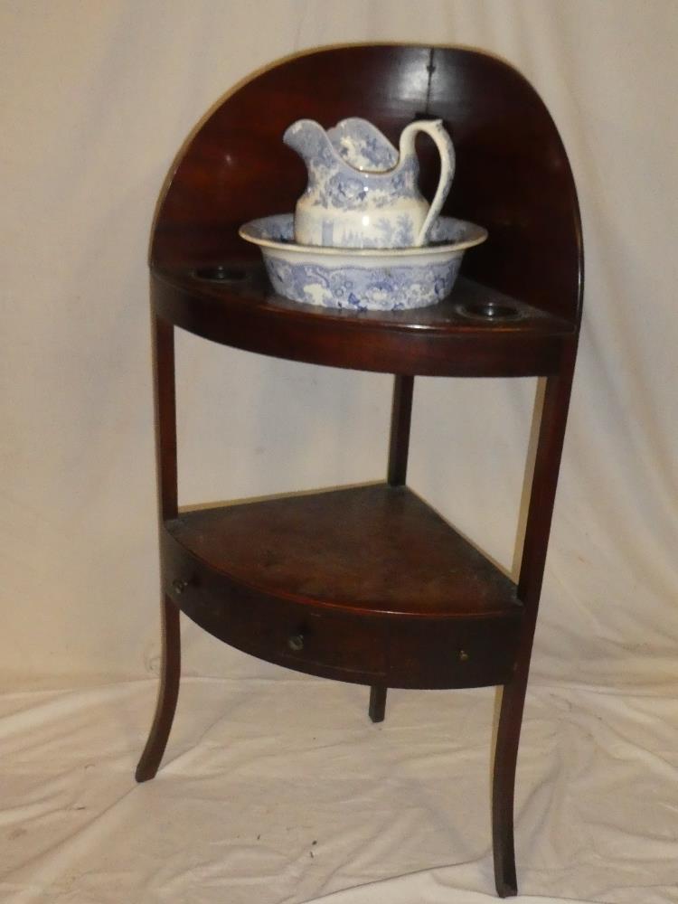 A 19th Century mahogany curved two tier wash stand with bowl recess supporting a blue and white