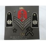 A display of Royal Marine Light Infantry badges including brass title, cap badge,