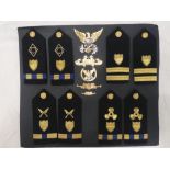 A display of United States Coastguard badges including cap badges, shoulder boards,