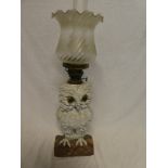 A Continental china oil lamp in the form of an owl with brass mounts and frosted glass shade,