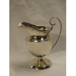 A George V silver pedestal cream jug with scroll handle on circular base,