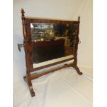 A bevelled rectangular toilet mirror on mahogany turned supports