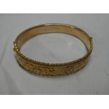 A 9ct gold oval bangle with engraved decoration,