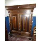 A good quality Continental carved oak housekeeper's cupboard with shelves enclosed by two panelled