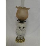 A Continental china oil lamp in the form of an owl with brass mounts and pink tinted glass shade,