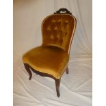 A Victorian carved mahogany salon chair upholstered in gold buttoned fabric on scroll shaped legs