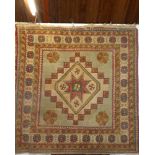An Eastern hand knotted wool rug with geometric and floral decoration on red,