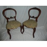 A set of five Victorian walnut balloon back dining chairs with carved rail backs and upholstered