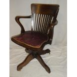 An Edwardian oak swivel office chair with rail back and leather cloth upholstered seat