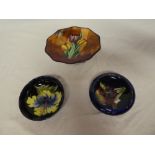 Two Moorcroft pottery circular shallow bowls with floral decoration (both damaged) and a small