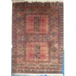 An Eastern wool rug with geometric decoration on red ground,