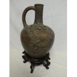 An old Eastern terracotta tapered flagon with raised dragon decoration 14" high on wooden stand