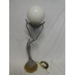 A modern aluminium Art Deco-style table lamp in the form of a scantily clad female holding a sphere
