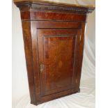 A George III oak and mahogany hanging corner cupboard with shelves enclosed by a central panelled
