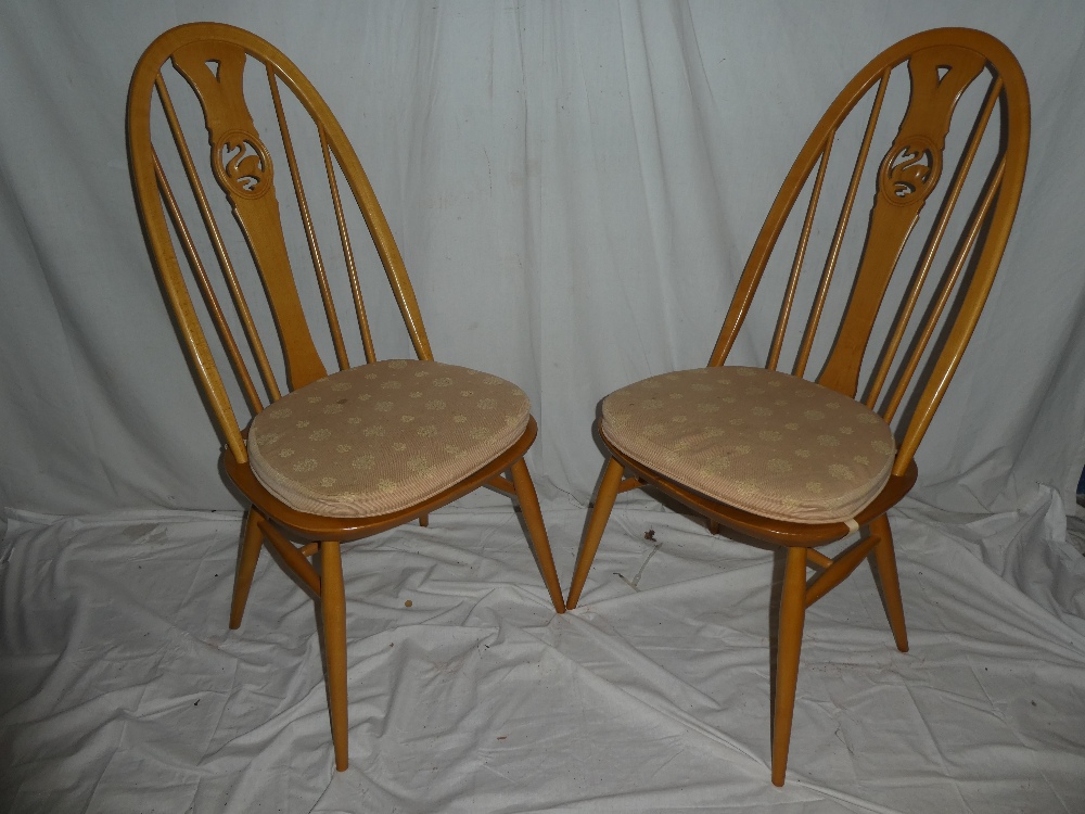A set of four Ercol light elm dining chairs with arched backs,