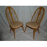 A set of four Ercol light elm dining chairs with arched backs,