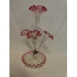 A cranberry tinted glass epergne with central trumpet spill flanked by three smaller spills on
