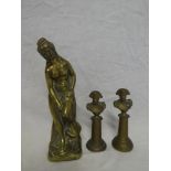 A brass figure of a scantily clad female,