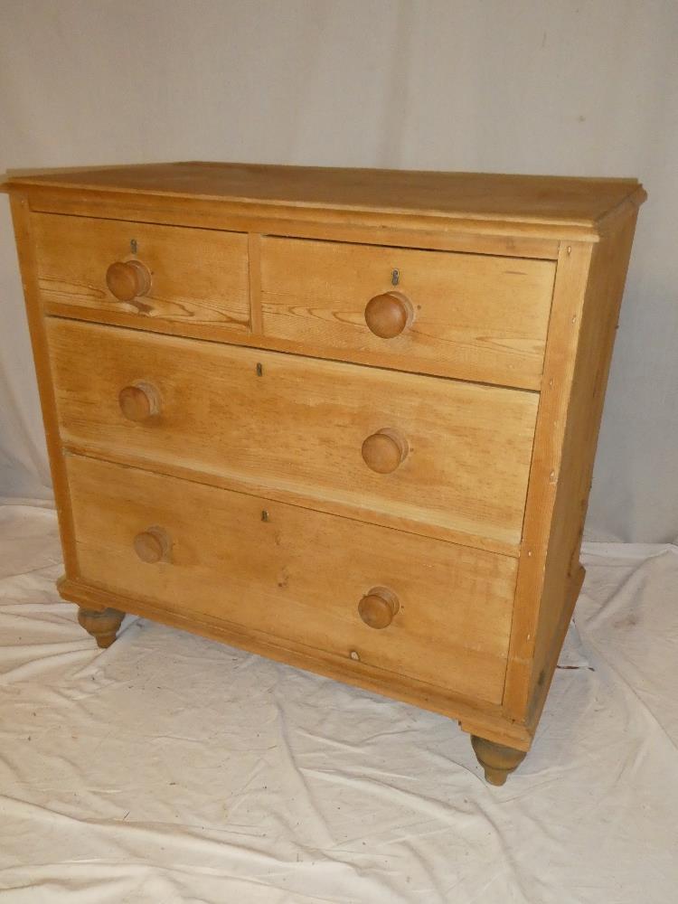 An old polished pine chest of two short and two long drawers with turned handles on turned feet