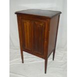 An Edwardian walnut music cabinet with shelves enclosed by a single panelled door