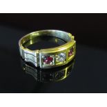 A gold ring centrally set with brilliant cut diamond flanked by round cut rubies in a square