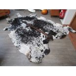 A cow hide rug in tan/black and white.