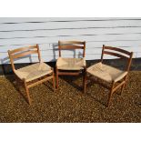 A group of three Danish oak dining chairs with woven paper cord seats