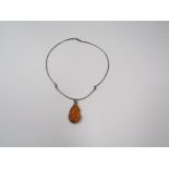 A contemporary white metal torc style choker necklace with large natural amber teardrop