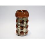 A studio glass vase, cinnamon coloured with metal jacket around dalek type body, domed exclusions,