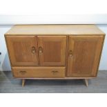 An Ercol side cabinet in light elm and beech, three cupboard doors and single drawer,