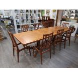 A Rosengaarden teak extending dining table together with eight slat back dining chairs.