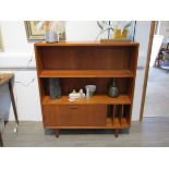 A Danish teak open bookcase/record cabinet, single drop down door, raised on tapering legs, 104.