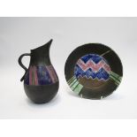 A studio pottery stoneware matt black glazed jug and dish with coloured geometric design.