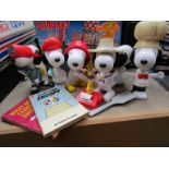 A collection of plastic Snoopy figures and two books